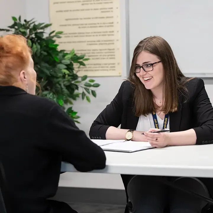 Two people seated at a table and talking.